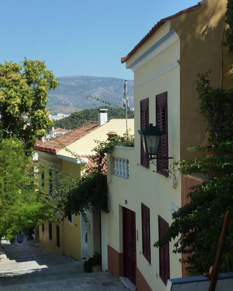 Rua do bairro de Plaka, em Atenas, com casas antigas e árvores
