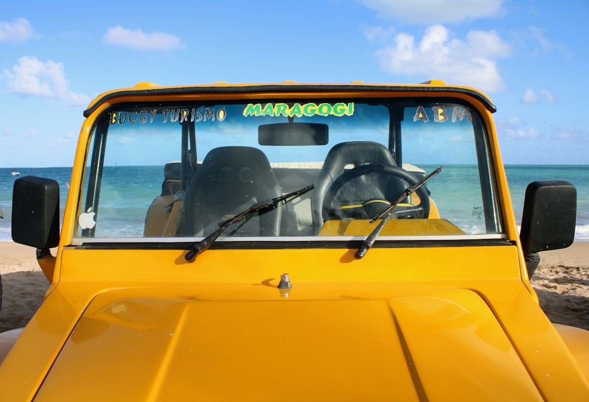 Buggy amarelo de passeio estacionado na praia em Maragogi