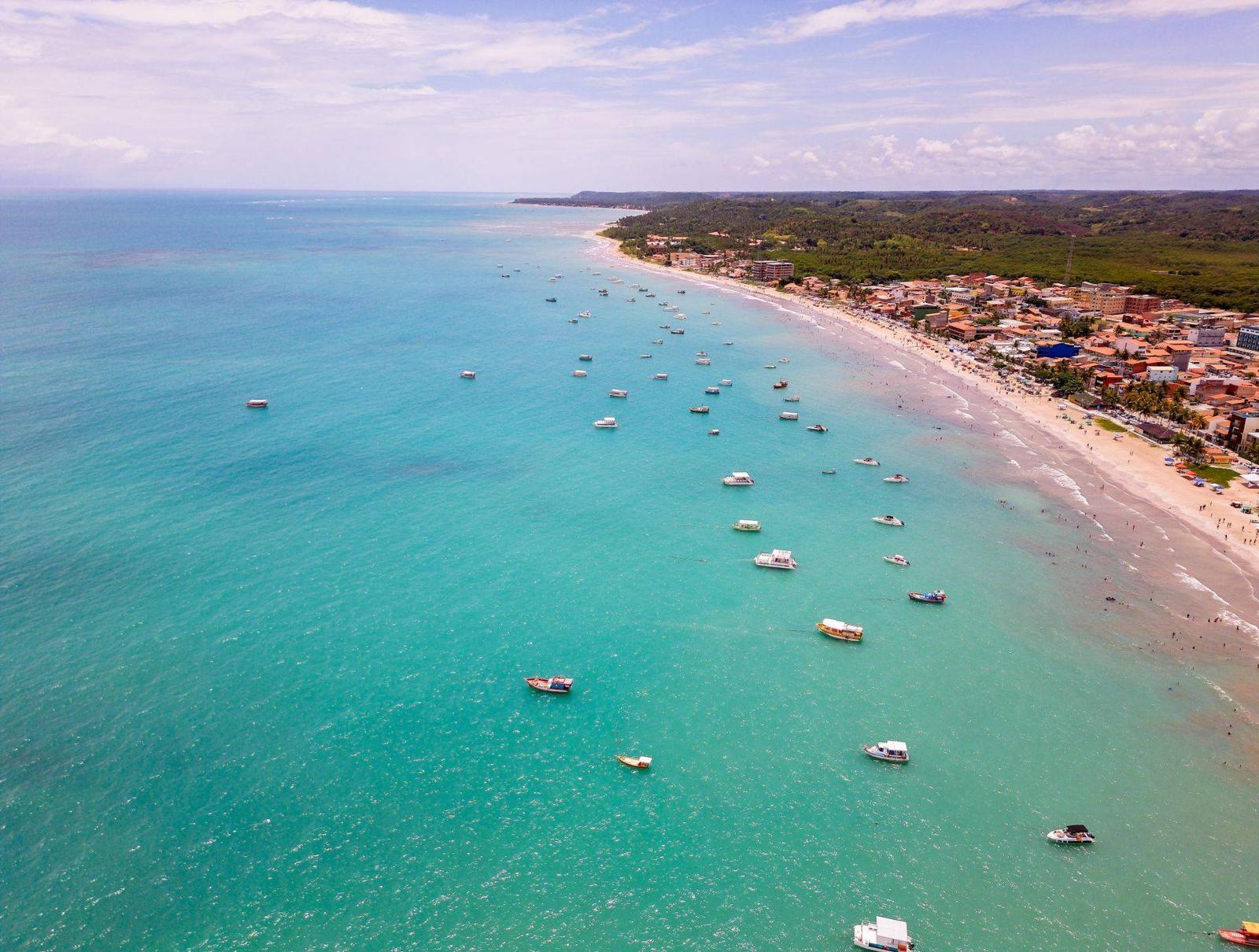 Vista aérea da orla de Maragogi com mar azul-turquesa e barcos