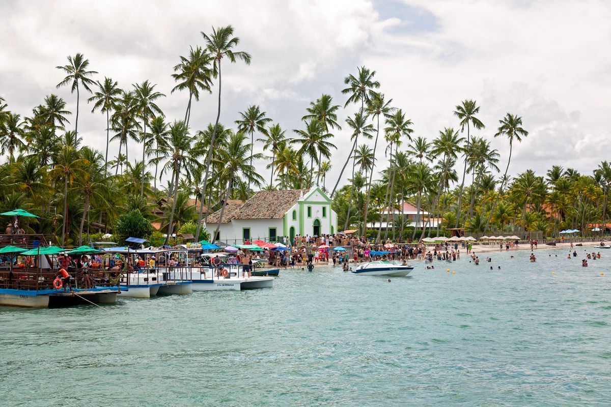 Praia e igreja de São Miguel dos Milagres com barcos e coqueiros