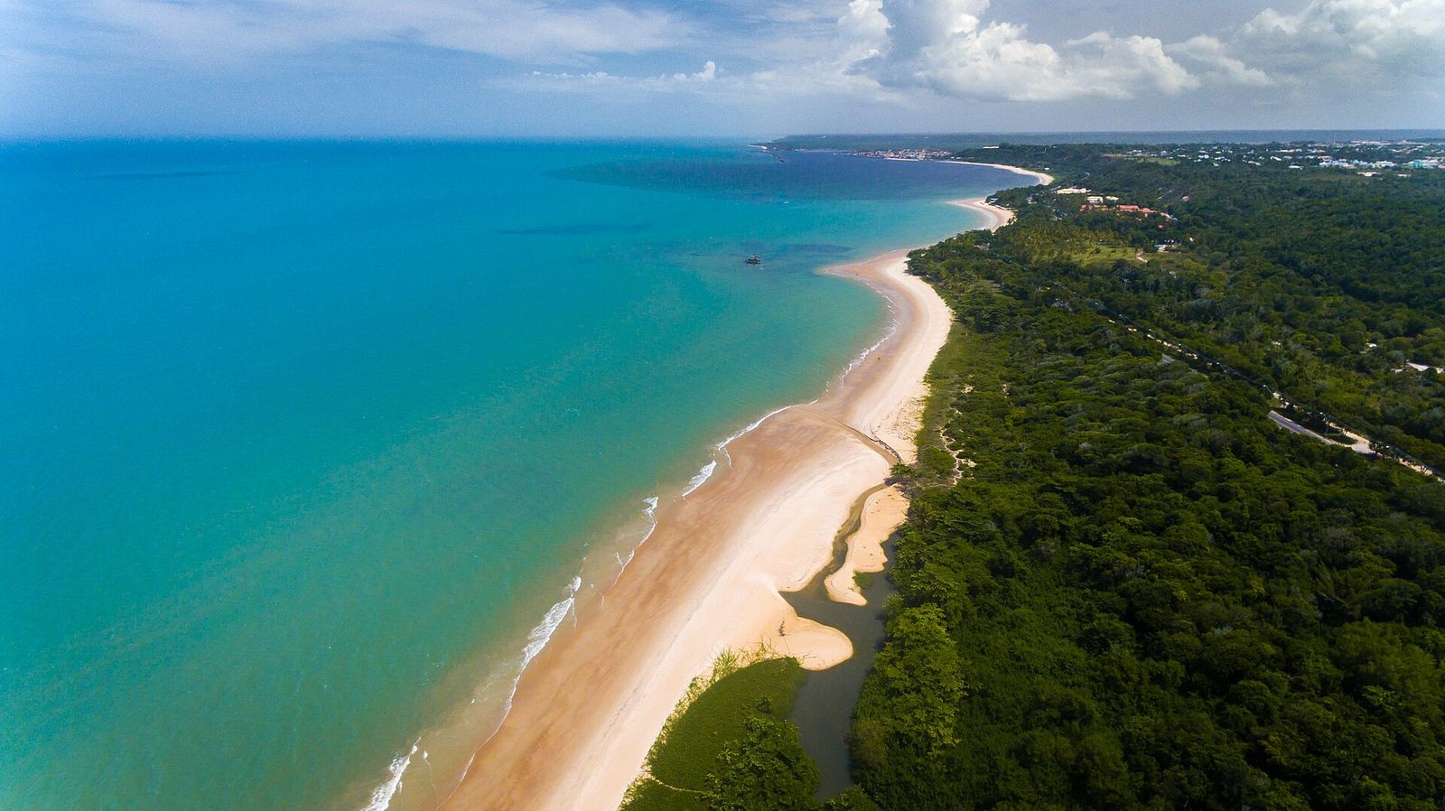 Vista aérea da orla de Porto Seguro, com faixa de areia clara e mar verde-azulado