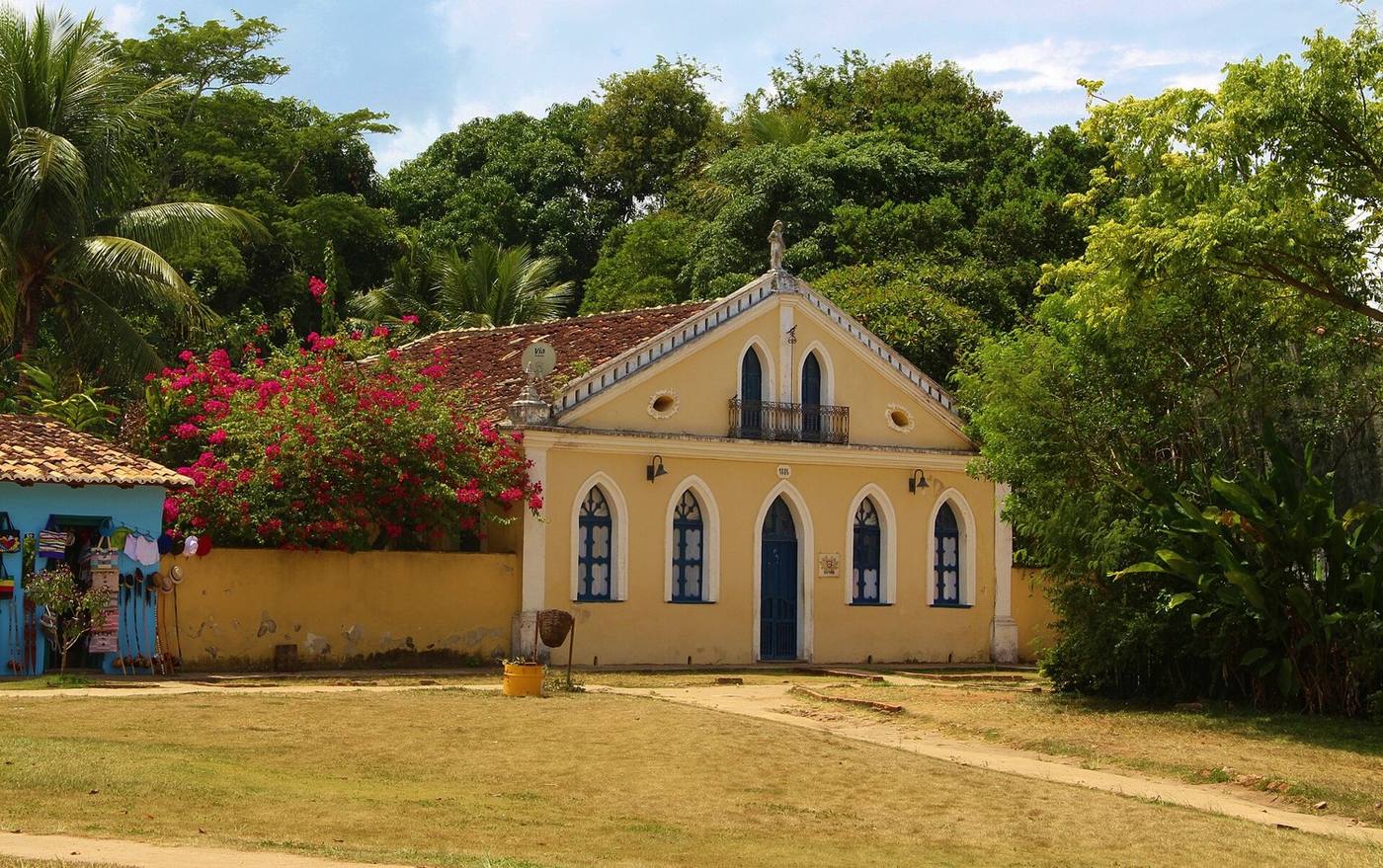 Casa colonial amarela com janelas em arco e buganvília florida, na Cidade Histórica de Porto Seguro
