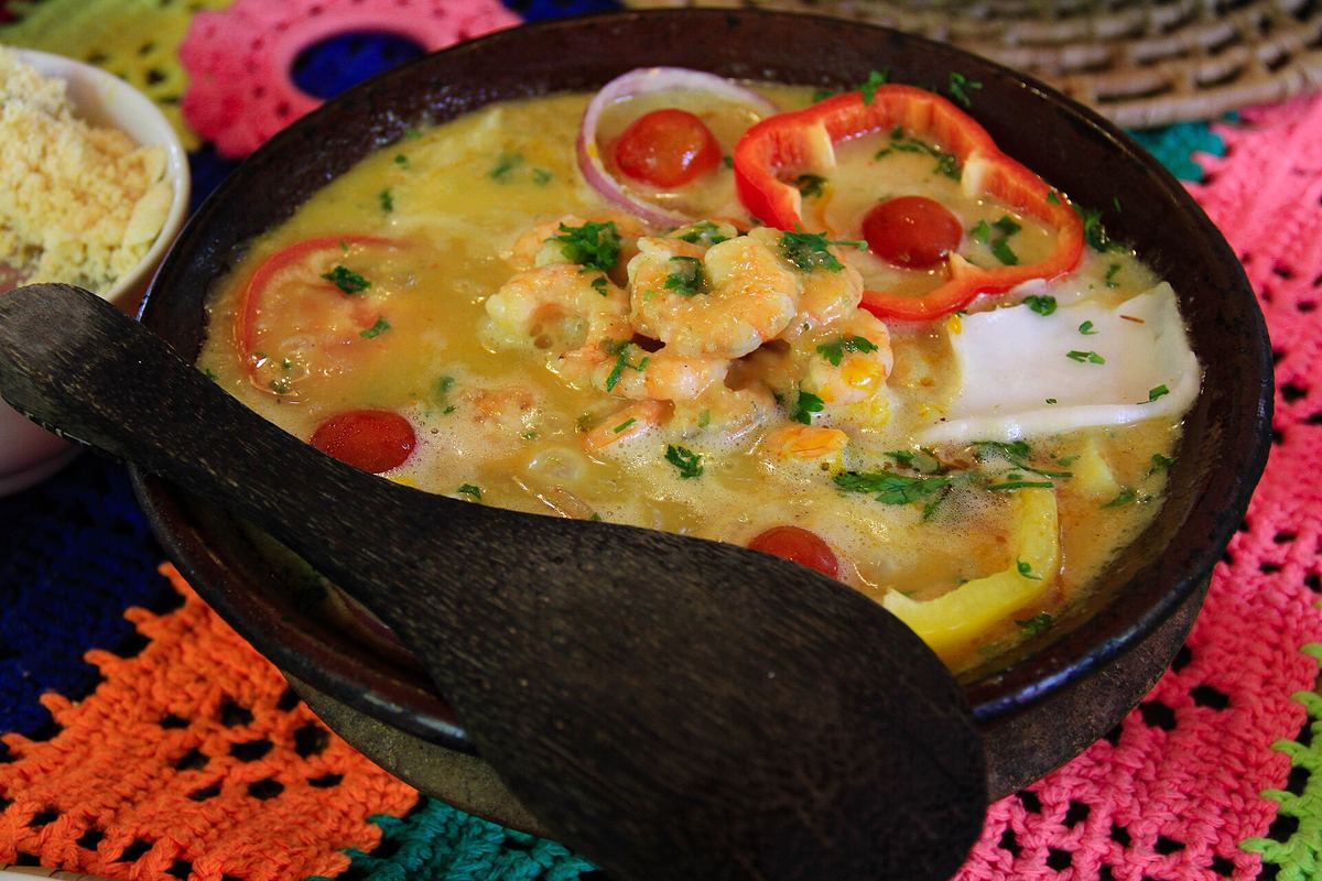 Moqueca de frutos do mar servida na panela de barro, com camarão, pimentão e tomate